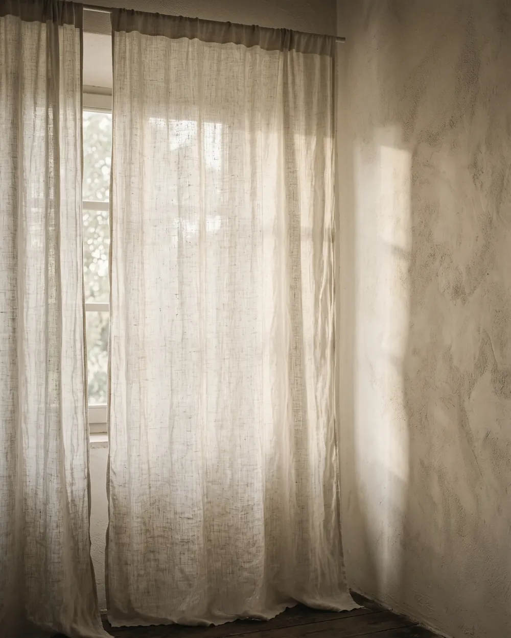 Una finestra con la tenda mossa dalla luce